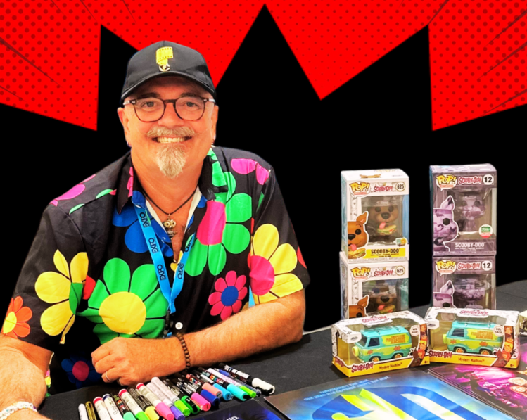 Actor Neil Fanning in flowers shirt at booth ready to sign autographs
